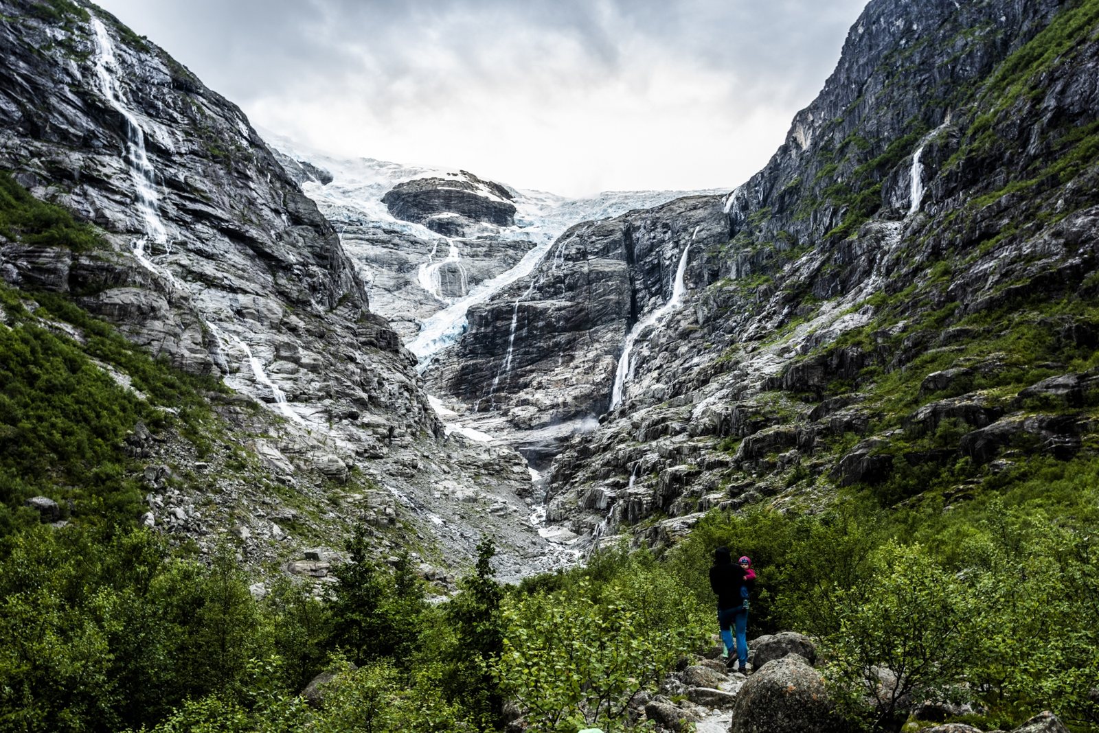 Wanderer in einem grünen Tal unter einem Gletscher in Norwegen