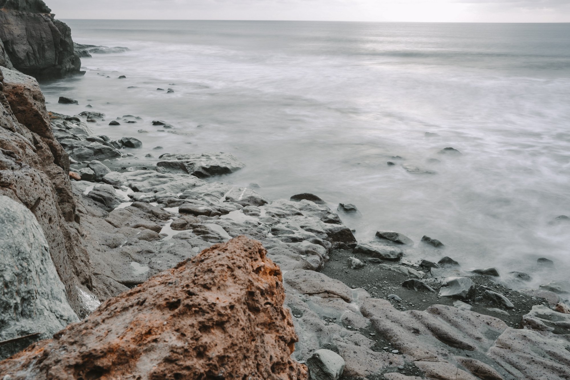 Felsige Küste mit glattgezogenem Meer durch lange Belichtungszeit